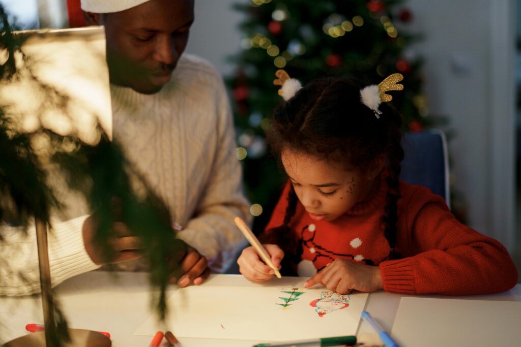 A father and daughter bond over drawing Christmas crafts indoors, capturing holiday spirit and family togetherness.