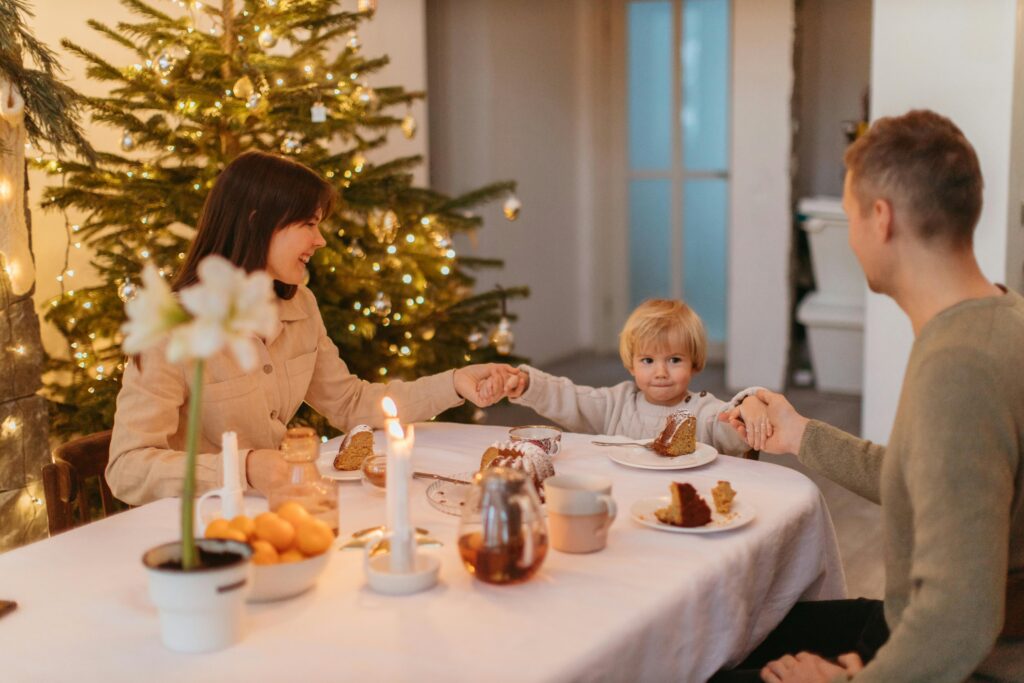Family enjoying a festive meal by a Christmas tree, sharing love and togetherness.